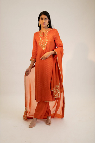 Rust embroidered straight kurta paired with pants and dupatta.