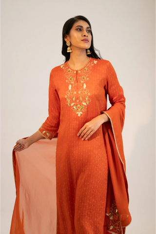 Rust embroidered straight kurta paired with pants and dupatta.